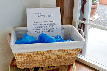 A box with shoe booties for buyer's and visitors to cover the bottom of shoes in a home listed for sale.