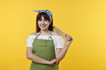 Happy woman with rolling pin on yellow background
