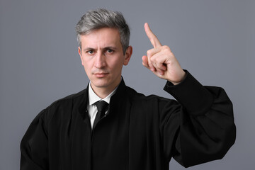 Judge in court dress shaking finger on grey background