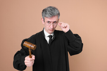 Emotional judge with mallet on beige background