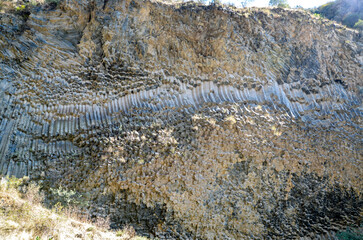 Hexagonal basalt column formations displayed on weathered cliff, showcasing unique geological patterns and structures resulting from volcanic activity and natural erosion. Symphony of stones, Armenia