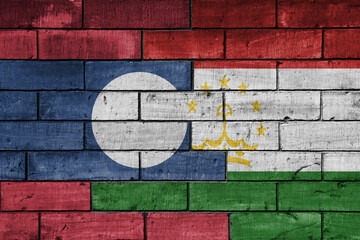 colourful painted big national flag of tajikistan and flag of laos on a massive old brick wall background. concept