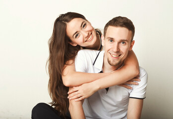 Happy man carrying his girlfriend on back. Young couple having fun together, posing and looking at camera