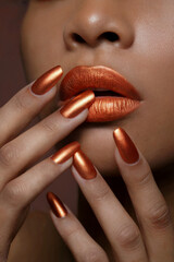 Naklejka premium A close-up beauty shot focusing on metallic copper-colored nail polish and lips. 