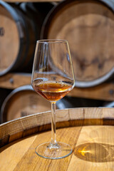 Visit of wine cellar with old large oak barrels, glass of fortified dry or sweet tasty marsala wine from barrels in Marsala, Sicily, Italy