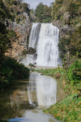 Majestic Hunua Falls waterfall cascades into a river surrounded by lush native forest,showcasing natural beauty and power. , Hunua, Auckland, New Zealand