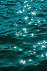 Sunlight sparkling on gentle rippling deep blue water surface creating glistening bright reflections