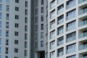 Modern high-rise residential buildings with numerous balconies and windows clustered together under clear daylight conditions