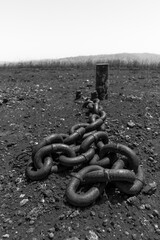 Rusty chain anchored to a weathered post in a desolate landscape