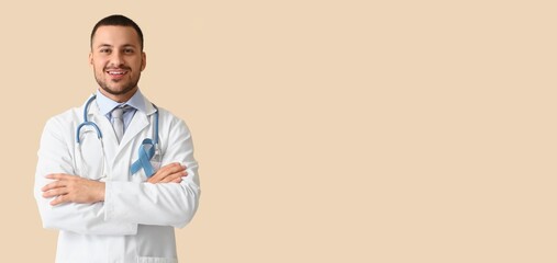 Male urologist with blue ribbon on beige background with space for text. Prostate cancer awareness...