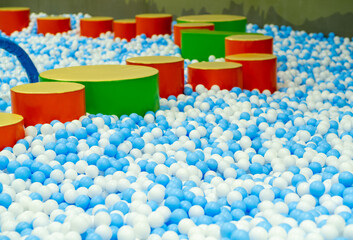 A vibrant indoor play space features a large ball pit filled with blue and white balls.