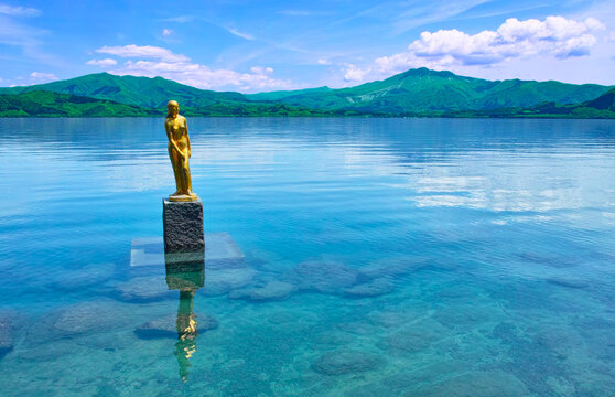 新緑の秋田県仙北市にある田沢湖、その湖畔に建つ黄金のたつ子像と秋田駒ケ岳。
