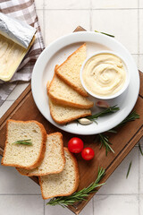 Wooden board with boxes of processed cheese, toasts and vegetables on white tile background
