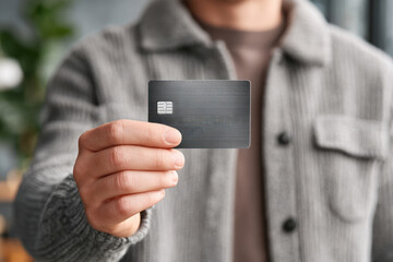 Person holding black credit card in hand showing digital payment concept for economy and financial transaction in modern life.