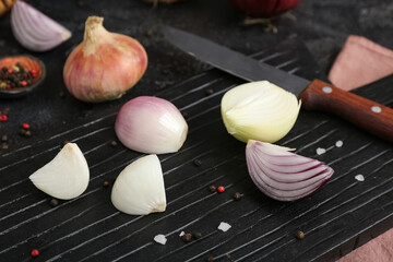 Board with different kinds of onion on grunge black background