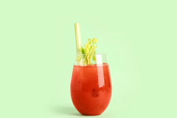 Glass of bloody mary with celery on green background