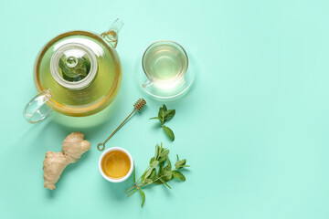 Teapot with cup of fresh mint tea, ginger root and honey on turquoise background