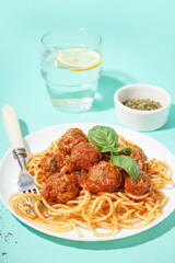 Plate of boiled pasta with tomato sauce and meat balls on blue background