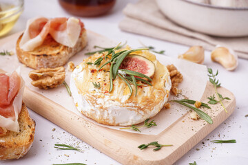 Wooden board with tasty baked Camembert cheese on grey background