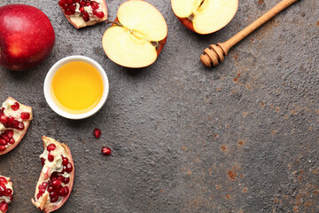 Bowl of honey with pomegranate and apples for Rosh Hashanah celebration (Jewish New Year) on dark background