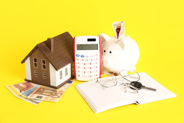 Calculator, house model, piggy bank, eyeglasses and money on yellow background. Mortgage concept