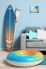 Interior of living room with grey sofa, surfing board and inflatable ring