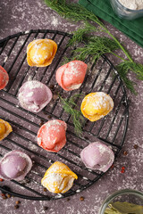 Stand of colorful raw dumplings with peppercorn and dill on dark background