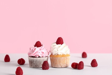Tasty raspberry cupcakes and fresh berries on pink background