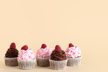Tasty cupcakes with raspberries on beige background