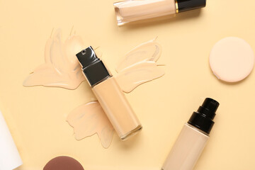 Obraz premium Bottles of makeup foundation with sponges and samples on beige background