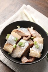 Pieces of delicious herring with green onions on wooden table, closeup