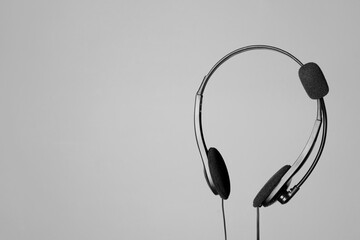 Headset with microphone in air on light grey background, space for text