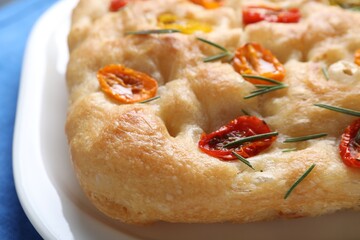 Delicious focaccia with tomatoes and rosemary on table, closeup