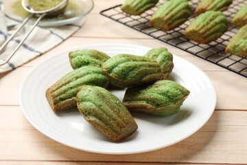Tasty matcha madeleine cakes on light wooden table, closeup