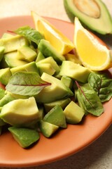 Tasty cut avocados, spinach and lemon on light textured table, closeup