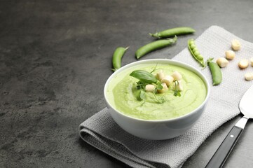 Tasty pea cream soup with croutons, basil and microgreens served on grey table. Space for text