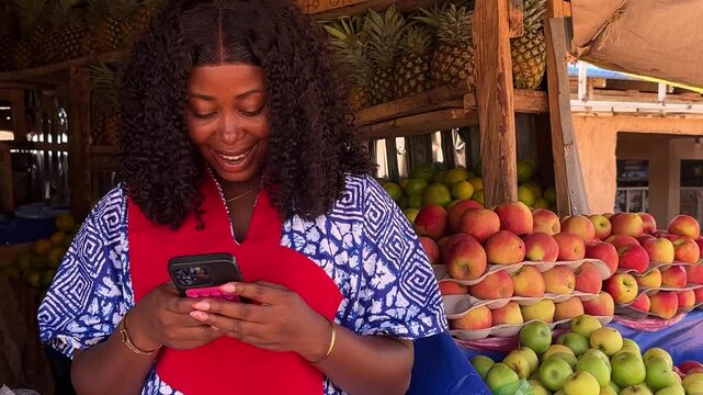 african market woman standing using phone while isolated over fruit stand