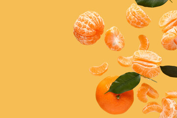 Flying sweet ripe mandarins and leaves on yellow background