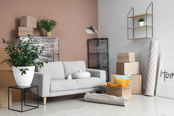 Cardboard boxes, picture and furniture in new living room on moving day