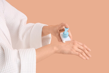 Woman applying cream onto her hands on color background, closeup