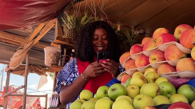 black attractive woman using phone at market fruit stand