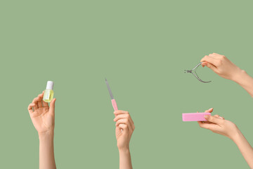 Female hands with bottle of cuticle oil, nail files and cutter on green background