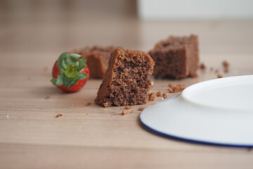 Chocolate cake slice with fresh strawberry spilled on wooden table
