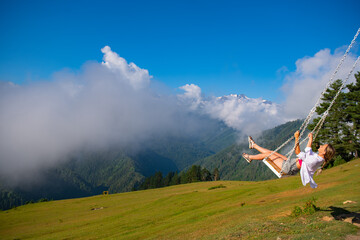 Girl swinging on a swing in the mountains of Georgia in Ushguli