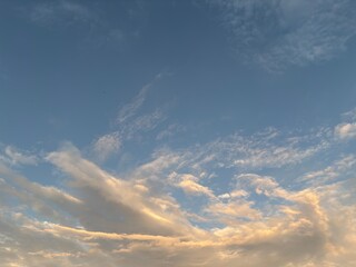 calm sky photo with soft and thin clouds golden light of the sun, light and shadow on the clouds create texture, bright blue sky calming background. Suitable for nature, tranquility, weather, freedom