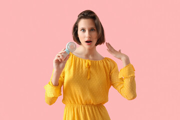 Young woman with portable electric fan on pink background