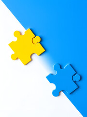 Photo of yellow and blue puzzle pieces on a white background, depicting a tangent line between them. The concept is classroom education with a focus on intelligence symbolized by geometric shapes