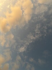 calm sky photo with soft and thin clouds golden light of the sun, light and shadow on the clouds create texture, bright blue sky calming background. Suitable for nature, tranquility, weather, freedom