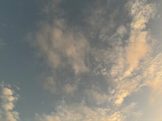 calm sky photo with soft and thin clouds golden light of the sun, light and shadow on the clouds create texture, bright blue sky calming background. Suitable for nature, tranquility, weather, freedom