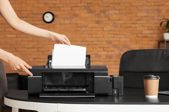 Businesswoman using printer on desk in office, closeup
